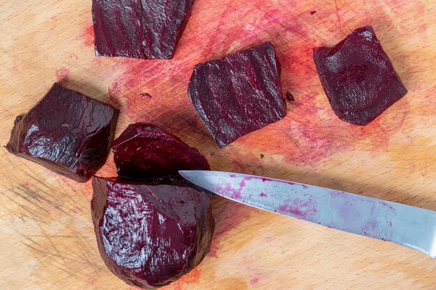 Barbabietole bollite rosse e coltello sul tagliere in cucina, primo piano, vista dall'alto