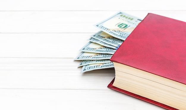 Red book with money on the white wooden table Space for text