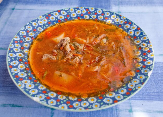 Photo red borscht on blue table