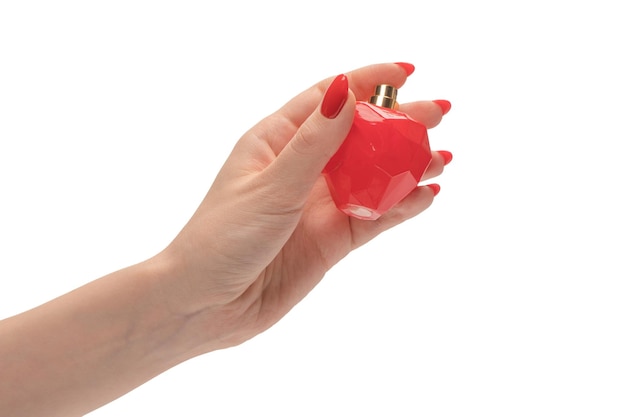 白い背景で隔離赤い爪を持つ女性の手で香水の赤いボトル