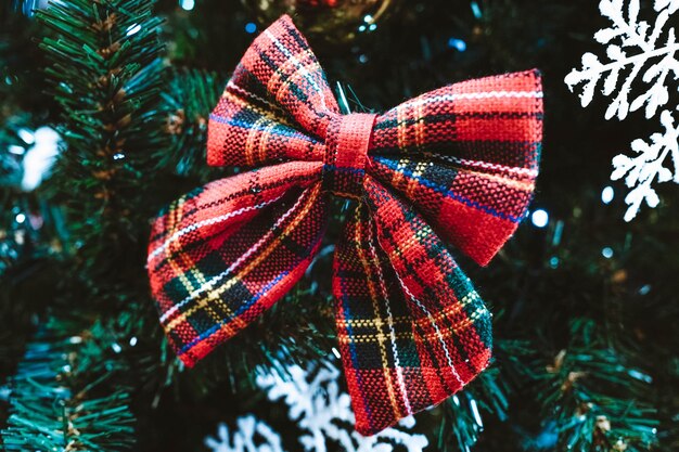 Photo red bow on the christmas tree. new year's composition. festive mood. winter holiday concept.