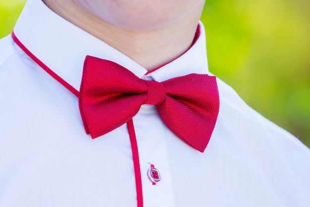 Red bow tie on a white shirt of a young man_