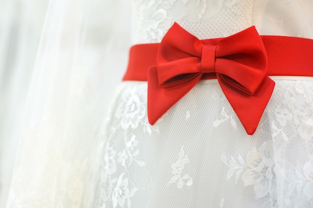 Red bow on wedding dress.