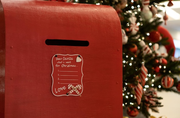 Red box on the background of the Christmas tree to collect mail for Santa Claus