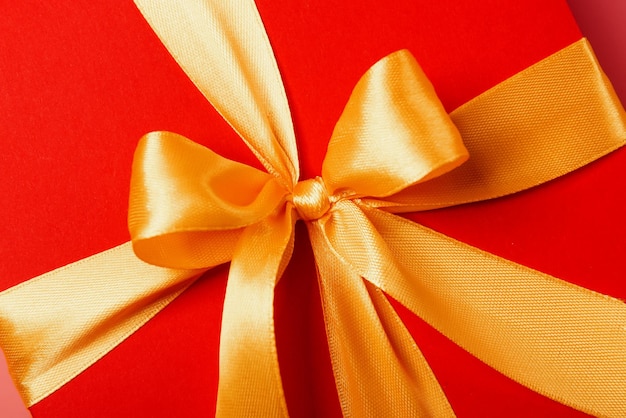 Red box tied with a gold ribbon. the ribbon is tied on a box in the form of a beautiful bow. holiday gift concept