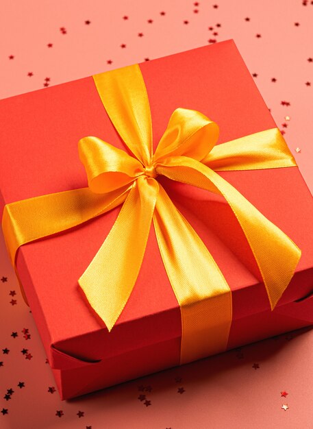 Red box tied with a gold ribbon. the ribbon is tied on a box in the form of a beautiful bow.
