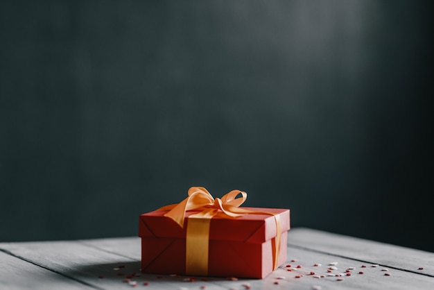 Red box tied with a gold ribbon. the ribbon is tied on a box in the form of a beautiful bow.