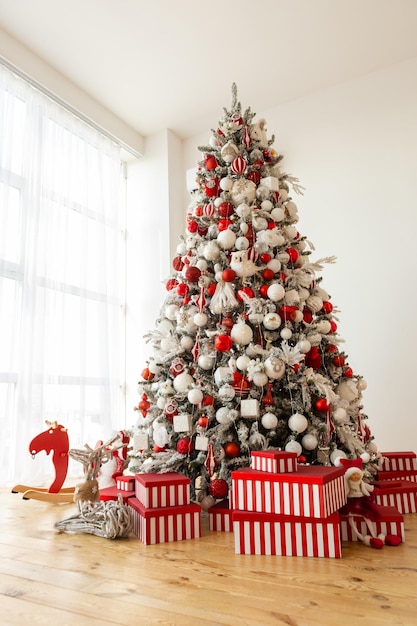 Red boxes with gifts christmas tree with white and red
decorations indoor christmas design big pine tree festive home
interior