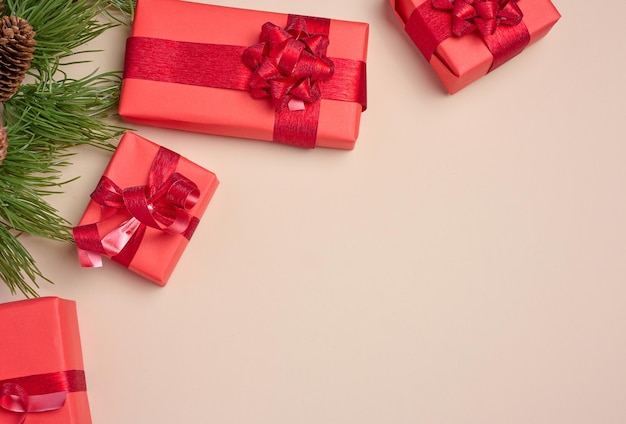 Photo red boxes with gifts fir branches with christmas decor on a beige background erhu view copy space