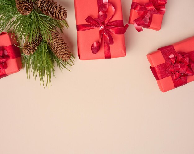 Red boxes with gifts fir branches with Christmas decor on a beige background erhu view