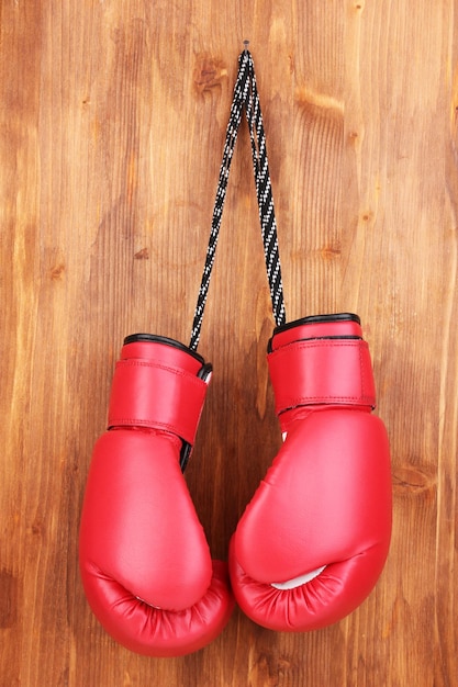 Red boxing gloves hanging on wooden background