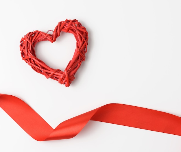 Red braided heart and twisted silk ribbon on white background, top view