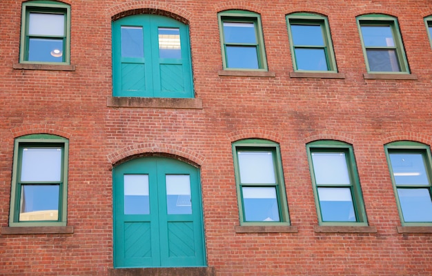 A red brick building with green windows and a green door.