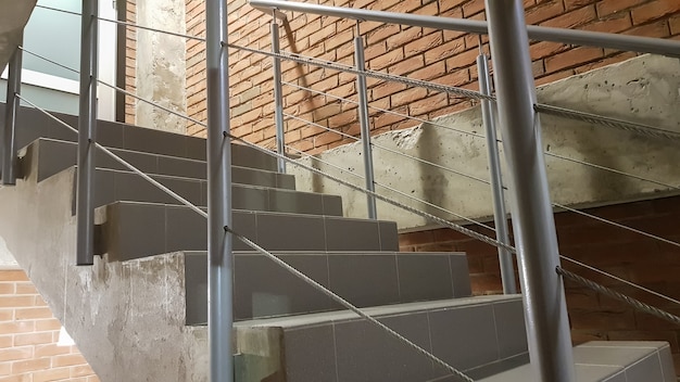 金属の手すりが付いたロフトスタイルのモダンな階段のある赤レンガ造りの建物。階段が建物を飾っています。モダンな階段。鋼の手すり。遠近法の階段。