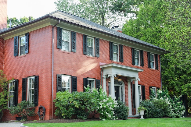 白いポーチと白いポーチが付いた赤レンガの家。