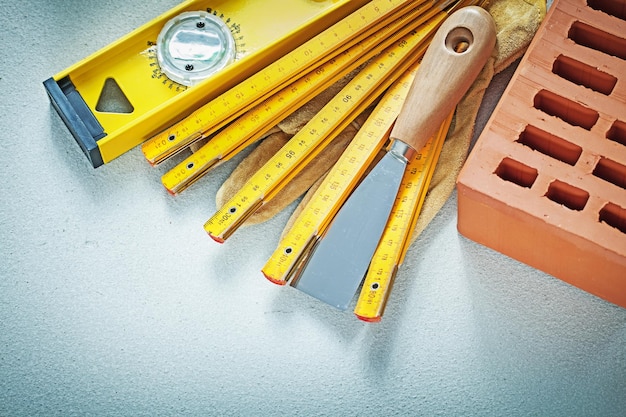 Red brick safety gloves putty knife construction level wooden meter on concrete background bricklaying concept