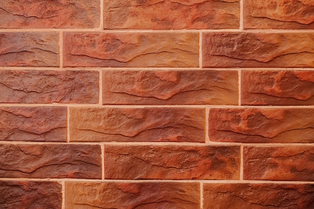 Red brick wall. Decorative brick with artificial defects and cracks. Texture of decorative tiles in form of brick