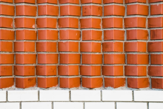 Red brick wall from diagonally angular bricks. geometric\
background image from brown horn bricks. compound with smooth white\
brickwork at bottom.