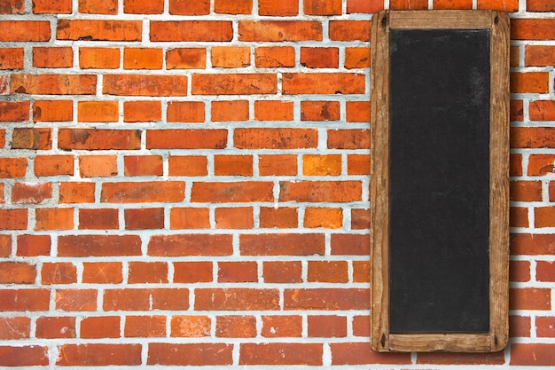 Red brick wall with vintage vertical blackboard sign