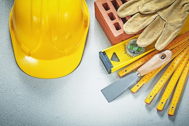 Red brick working gloves plastering trowel construction level wooden meter hard hat on concrete background