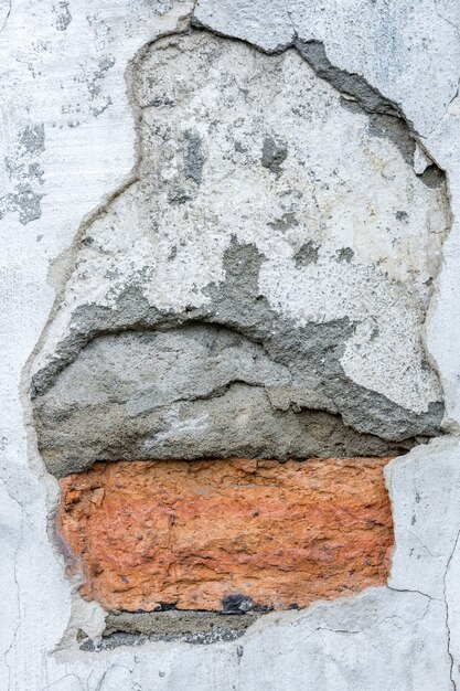 red brickwork under a layer of old crumbling plaster on the wall of the house