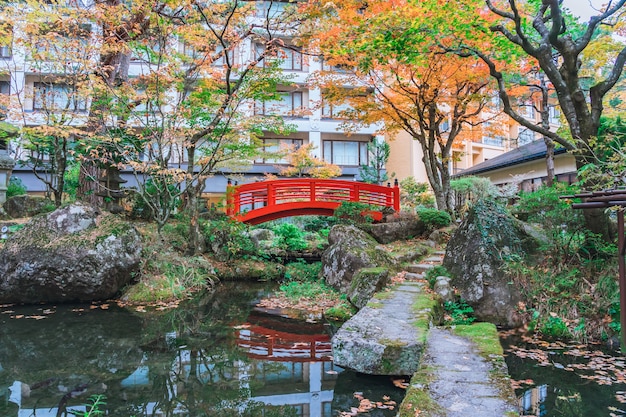 紅葉のある日本の緑豊かな公園の赤い橋、日本の秋の秋