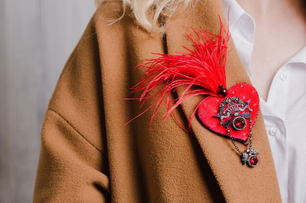 Red brooch on the collar of a camel-colored coat