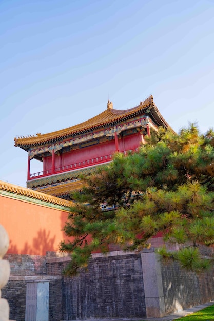 A red building with a red roof and a green tree in the foreground