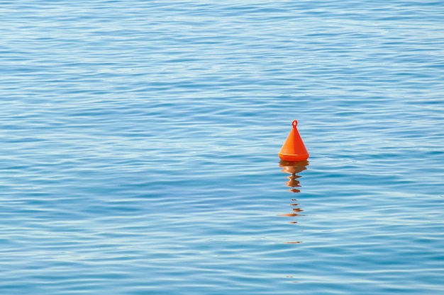 Red buoy floating on the surface of blue water in the sea