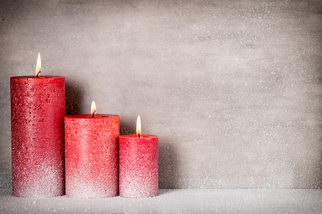 Red burning candle on a snow background. Interior items.