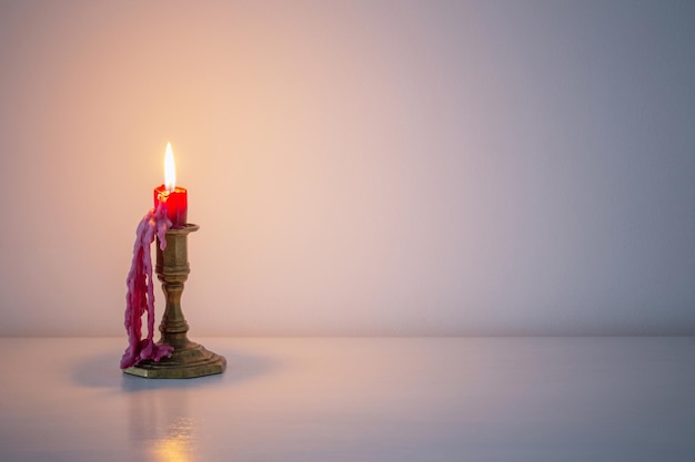 Red burning candle in white interior