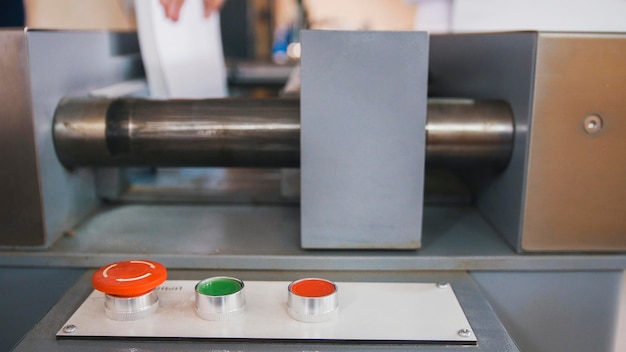 Red button on control panel of folding machine - printing polygraph industry, close up - telephoto