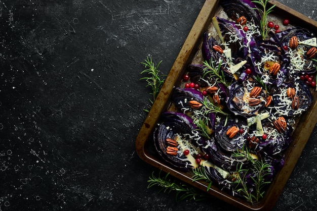 Red cabbage baked with blue cheese rosemary and nuts Top view On a black stone background