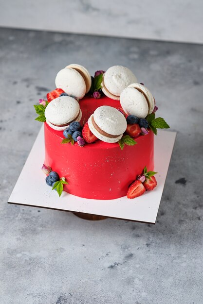 Red cake for a girl cake, decorated with macarons and fresh
berries. cake for the holiday. dessert is decorated with fresh
strawberries, blueberries and roses.