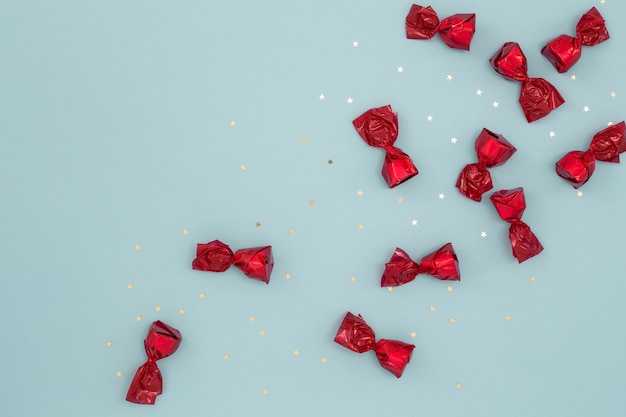 Red candies and gold confetti on blue surface