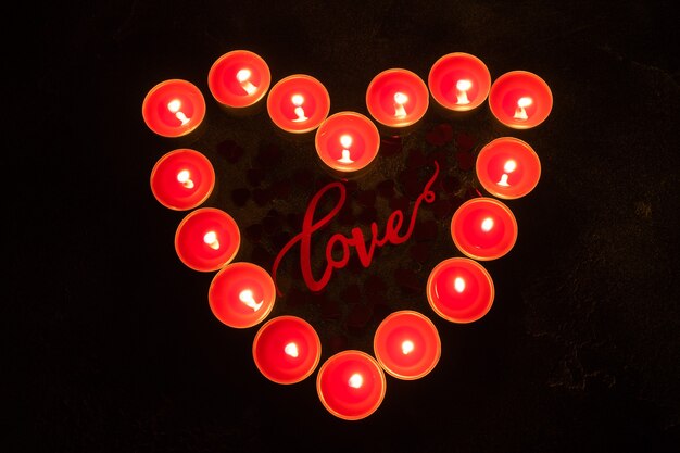 Red candles in the shape of heart on black surface, concept of Valentine's Day.