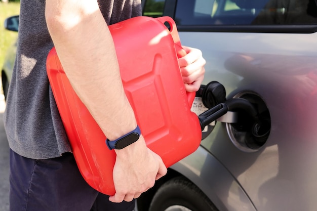 Photo a red canister on the asphalt near the car the car ran out of gas and stalled a young man hoping for help on the road from other drivers