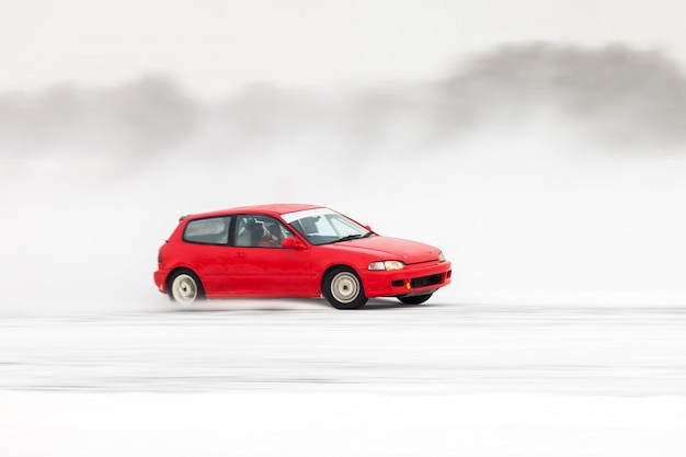 많은 얼음이 튀는 얼음 위를 움직이는 빨간 자동차