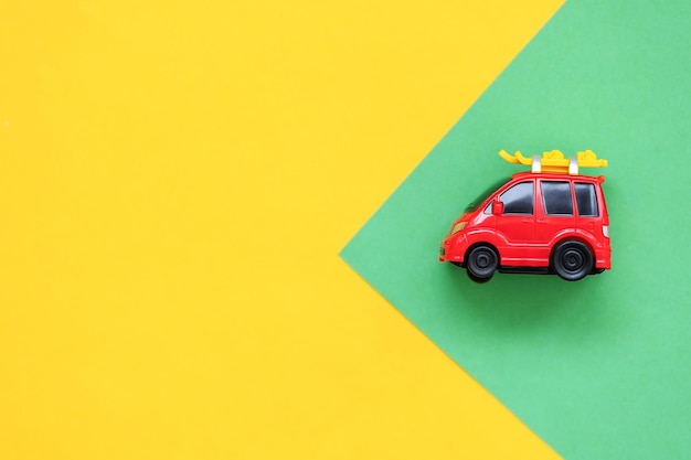 Фото Красный автомобиль на зеленом и желтом фоне концепция праздников и путешествий