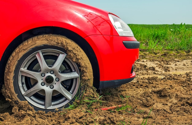 The red car stuck in the mud. Can not fall out of the mud