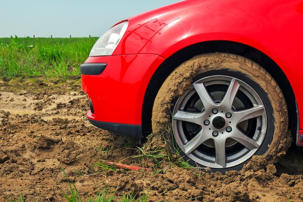 The red car stuck in the mud. Can not fall out of the mud