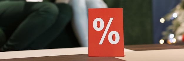 顧客のクローズアップ黒を背景に店内のテーブルに立っているパーセントの赤いカード