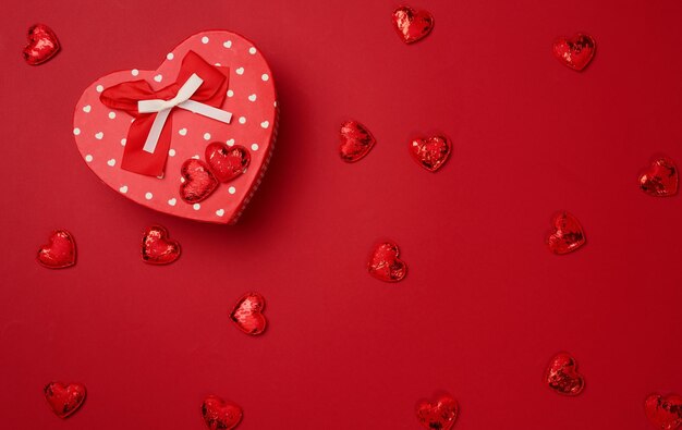 Red cardboard box with a gift on a red background top view