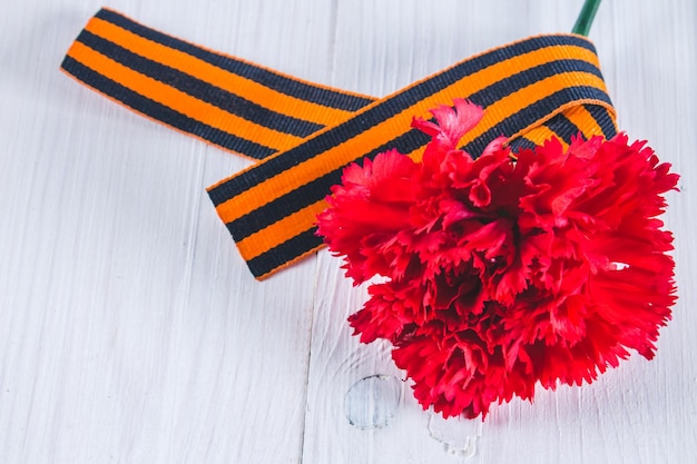 Red carnations tied with Saint George ribbon on gray