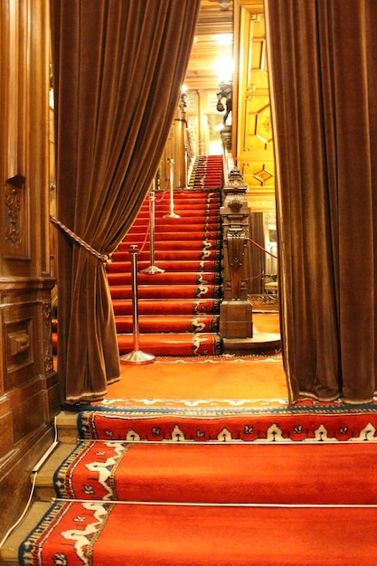 A red carpeted staircase with a curtained railing