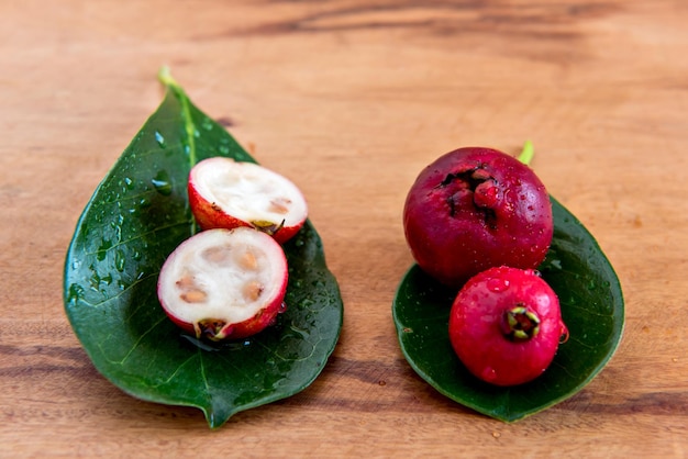 Red Cattley guava fruit and leaves on wooden bottom Psidium cattleyanum