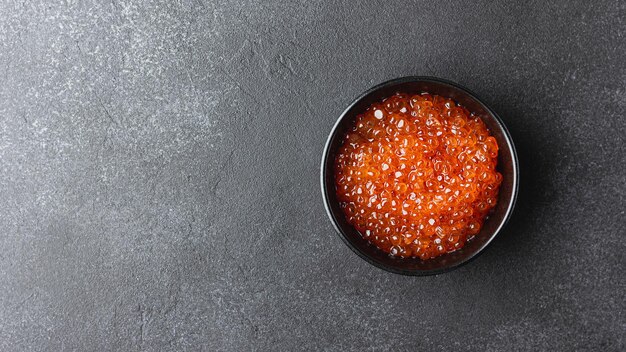 Red caviar in a black bowl