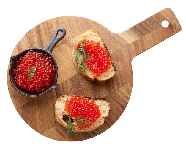 Red caviar in a black mini frying pan on a round wooden board top view concept of luxury and gourmet cuisine