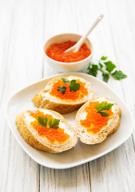 Red caviar in bowl and sandwiches 