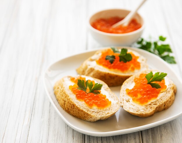 Red caviar in bowl and sandwiches 